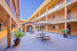 a courtyard with a table and umbrella in front of a building at Dronfield Astoria Apartments, Sylmar ,91342 - Photo Gallery 5