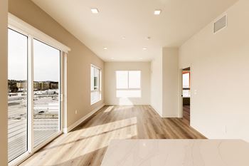 A large, empty room with a marble floor and a view of a parking lot through the windows.