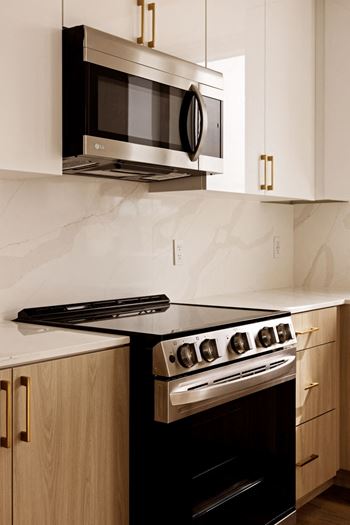 A modern kitchen with a black stove and a black microwave above it.