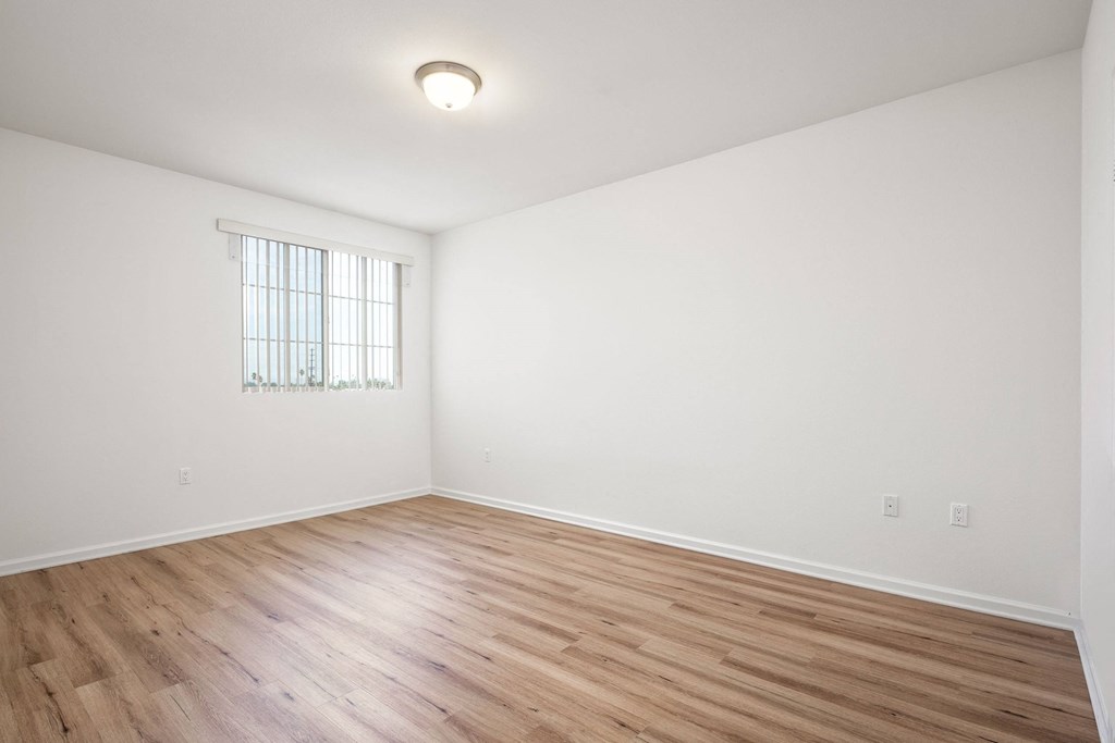 an empty living room with white walls and wood floors at Le Blanc Apartment Homes, Canoga Park, California