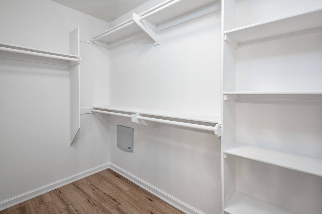 a walk in closet with white shelves and a wood floor at Le Blanc Apartment Homes, Canoga Park, California