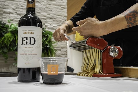 A bottle of Ed Emundo 2013 Cabernet Sauvignon is on a table next to a cup of wine and a pasta maker.