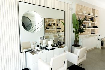 a living room with white furniture and a large mirror