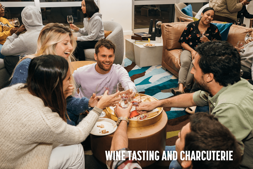 A group of people are gathered around a table enjoying a wine tasting and charcuterie event.
