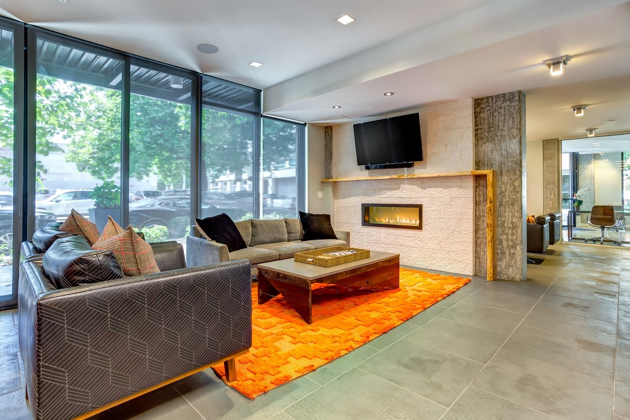 A modern living room with a grey couch and a fireplace.