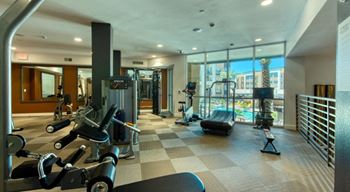 Upgraded gym with cardio equipment and a large window with a view of the city at Elevation SanTan