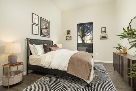 A bedroom with a large bed and a window showing a tree outside.