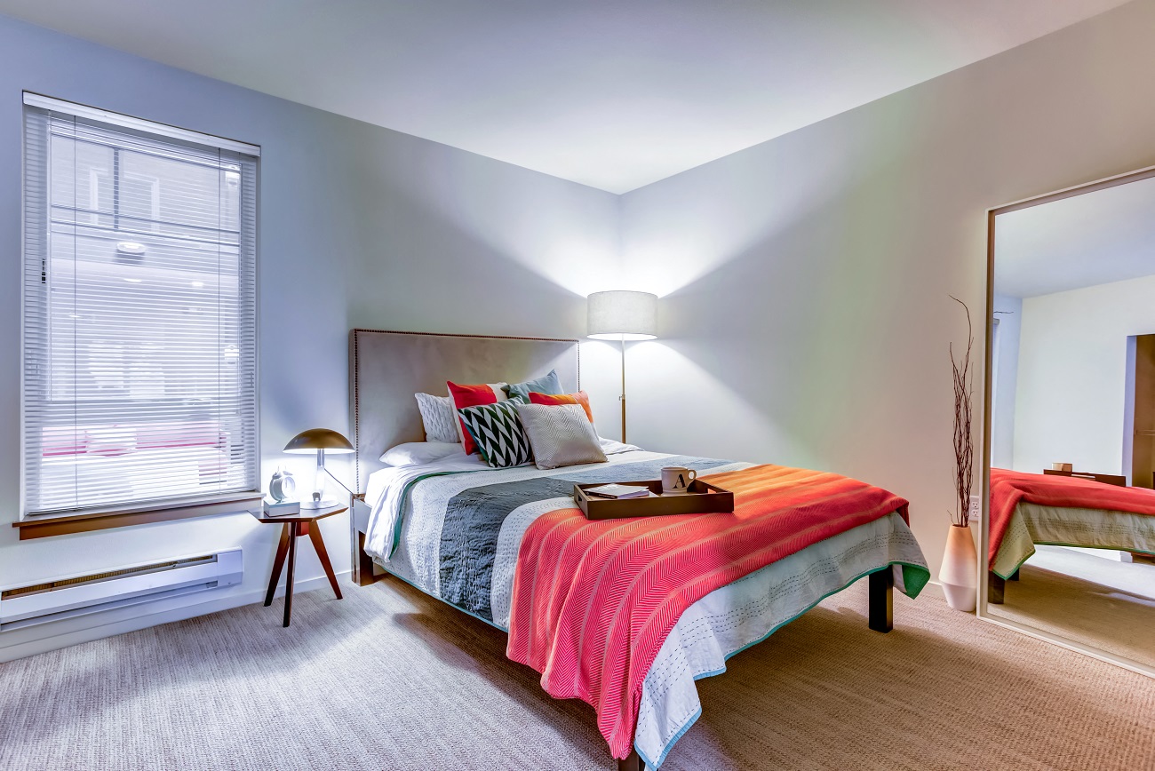 A bedroom with a bed, nightstand, and window