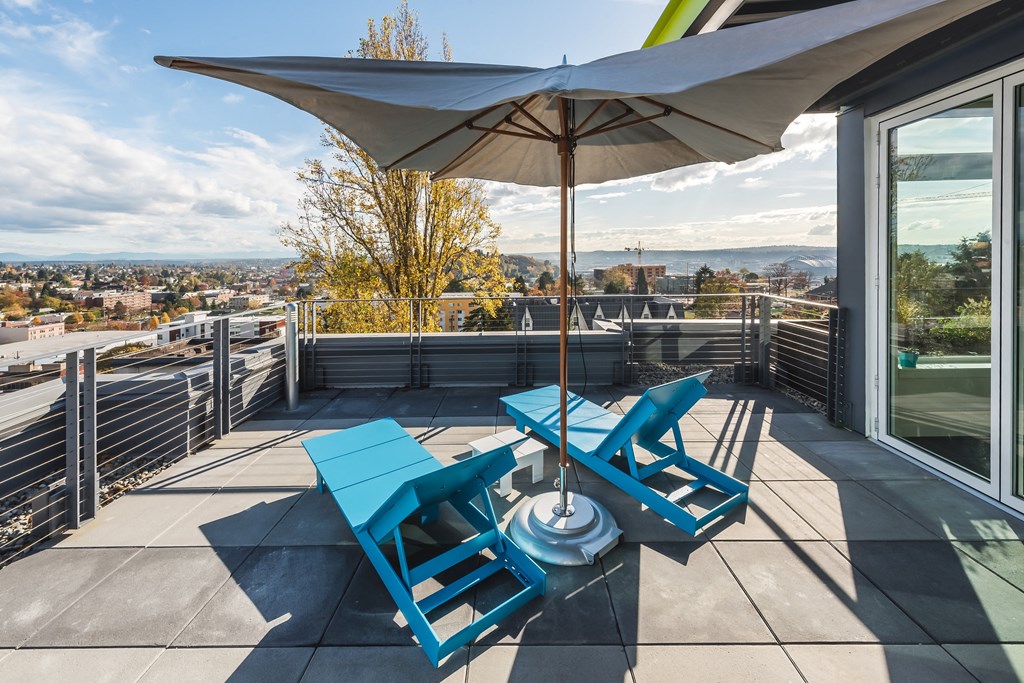a patio with two blue chairs and an umbrella on a balcony