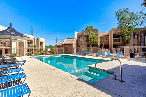 A swimming pool surrounded by blue chairs and a building in the background.