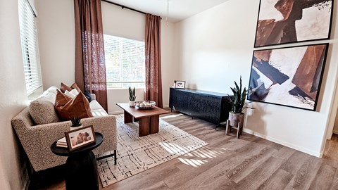 A living room with a brown sofa, a coffee table, and a painting on the wall.