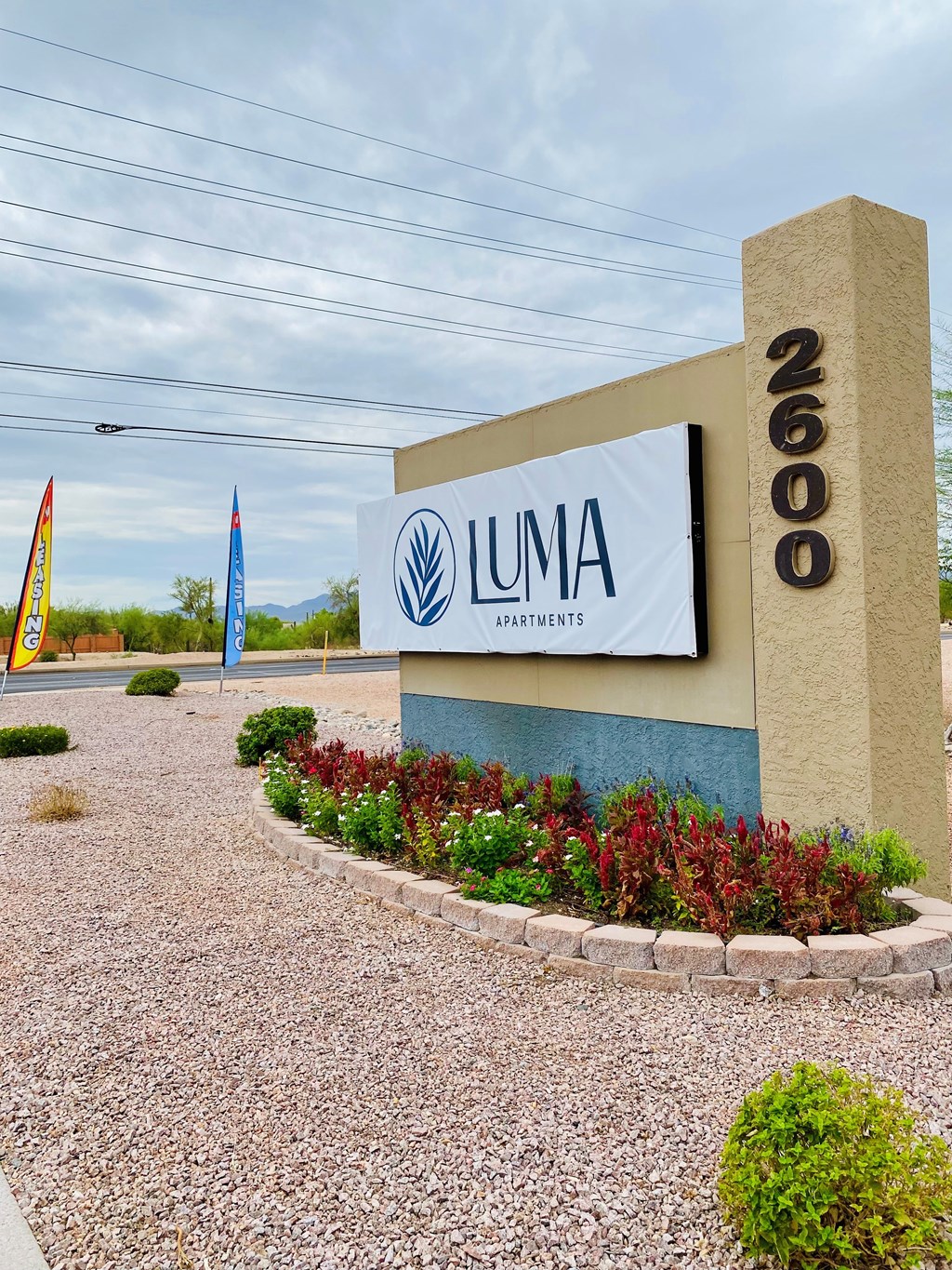 The image shows a sign for LUMA Apartments with a number 2600 on a pillar.