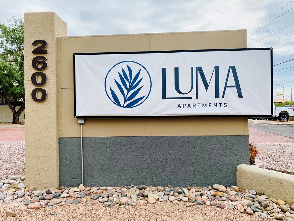A sign for Luma Apartments is displayed in front of a building.