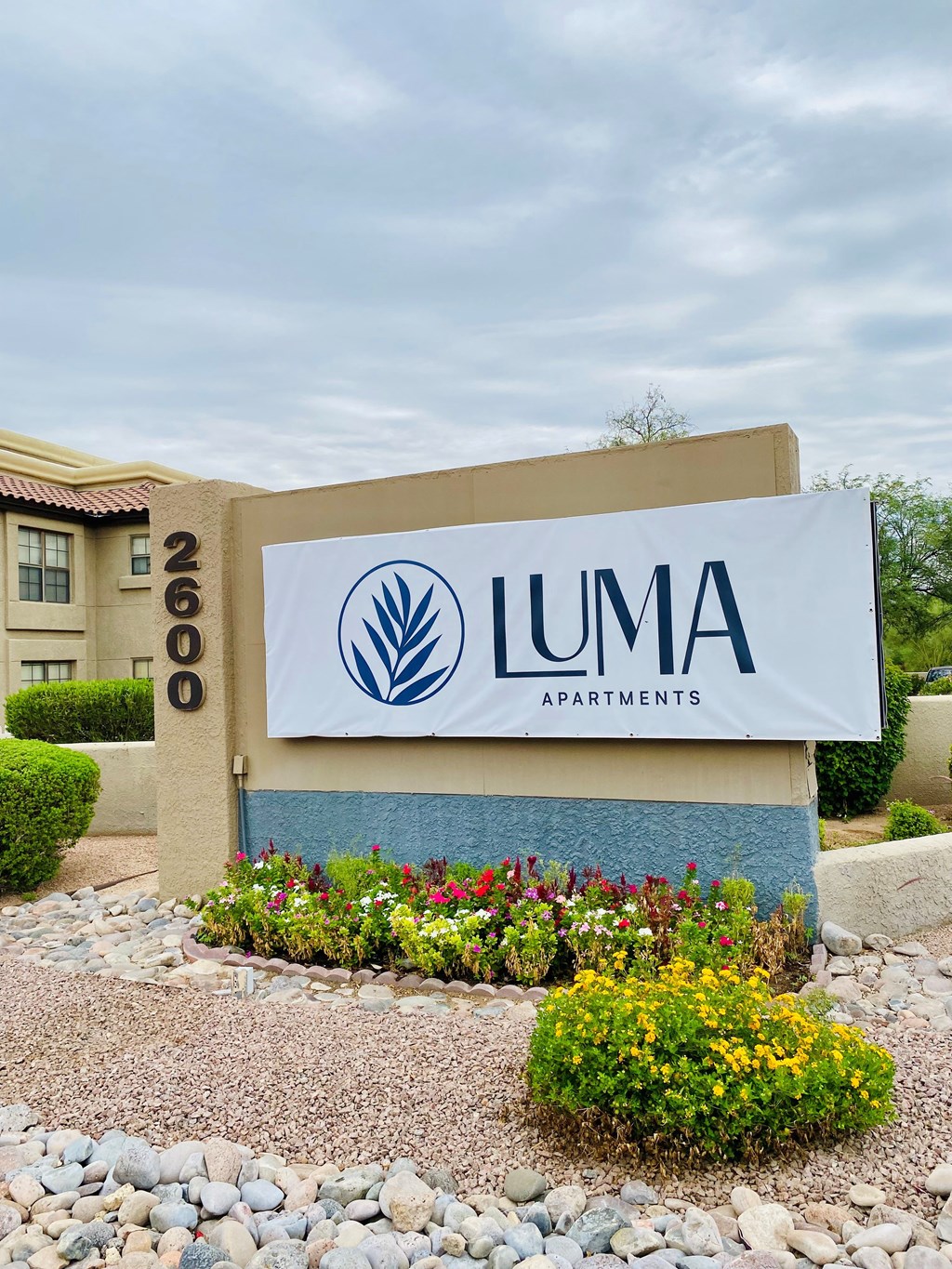 A sign for Luma Apartments is displayed in front of a building.