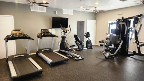 A gym with treadmills, elliptical machines, and other exercise equipment.