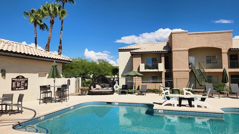 A pool with chairs and a building in the background.
