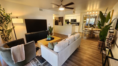 A living room with a white couch, a black television, and a ceiling fan.