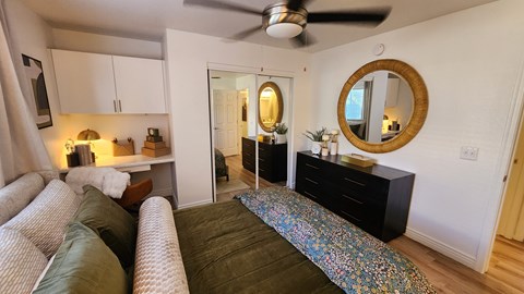 A living room with a couch, a mirror, and a ceiling fan.