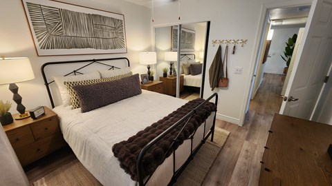 A bedroom with a large bed and a painting on the wall.