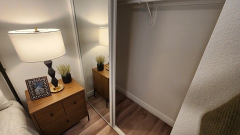 A lamp and a picture frame are on a wooden nightstand.