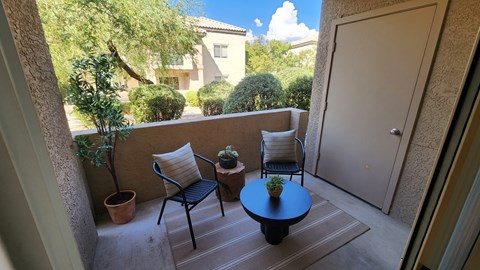 A patio with a table, chairs and potted plants.