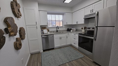 A kitchen with white cabinets and a refrigerator.