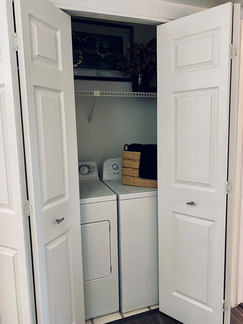 A white laundry cabinet with a basket on top of it.