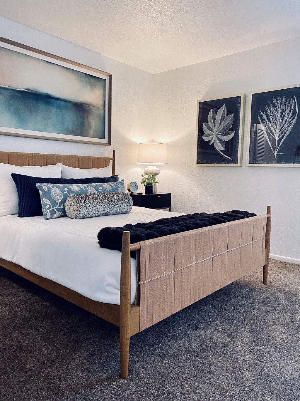 A bed with a white sheet and a black pillow is in the center of the image.