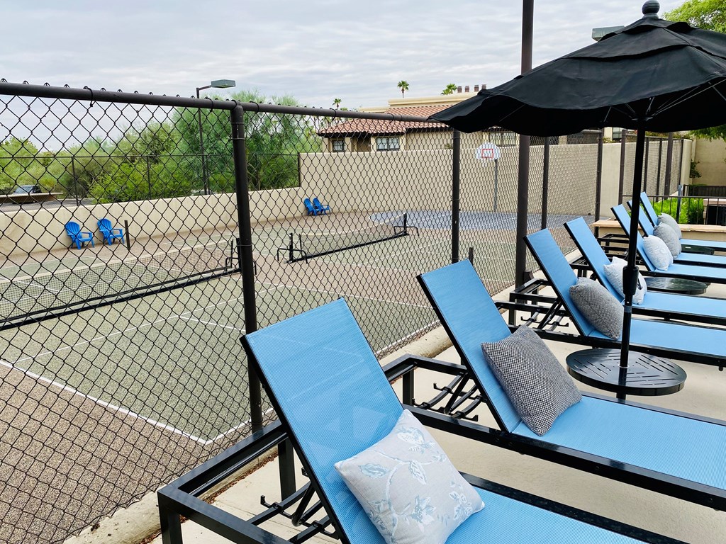 A row of blue chairs with pillows are on near pool.