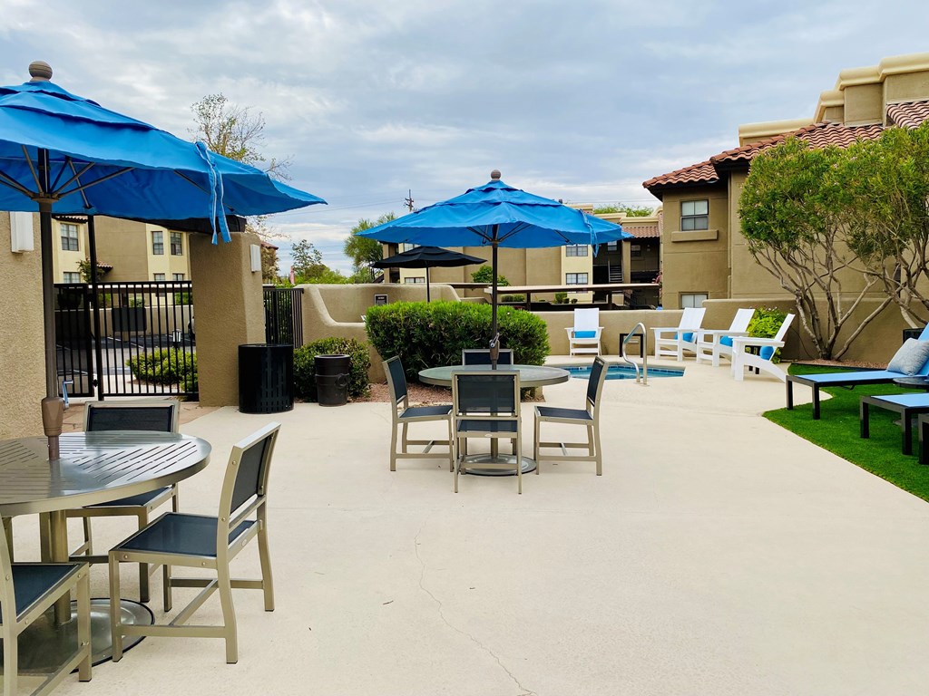 A patio with a table and chairs under umbrellas.
