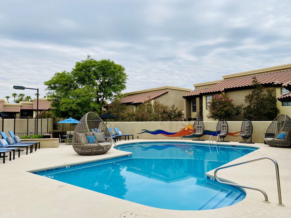 A pool with a blue tinted water and a white fence around it.