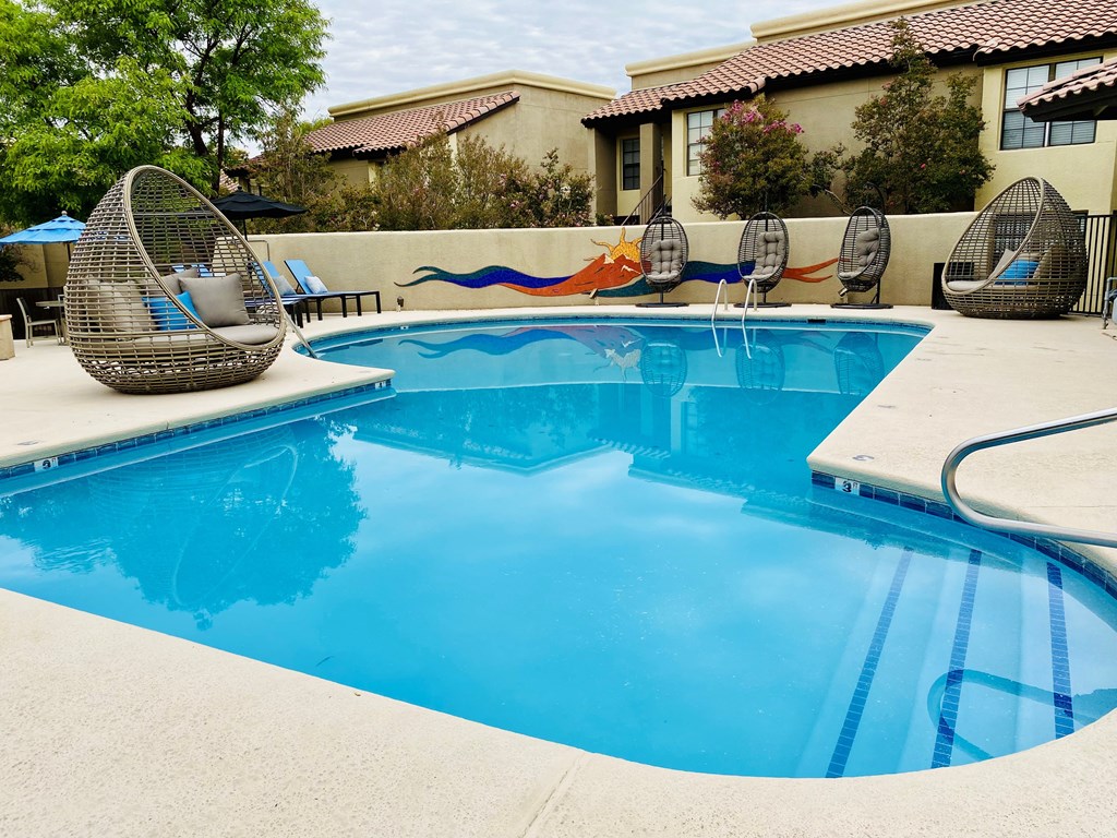 A blue swimming pool with a white edge and a white chair with a black armrest.