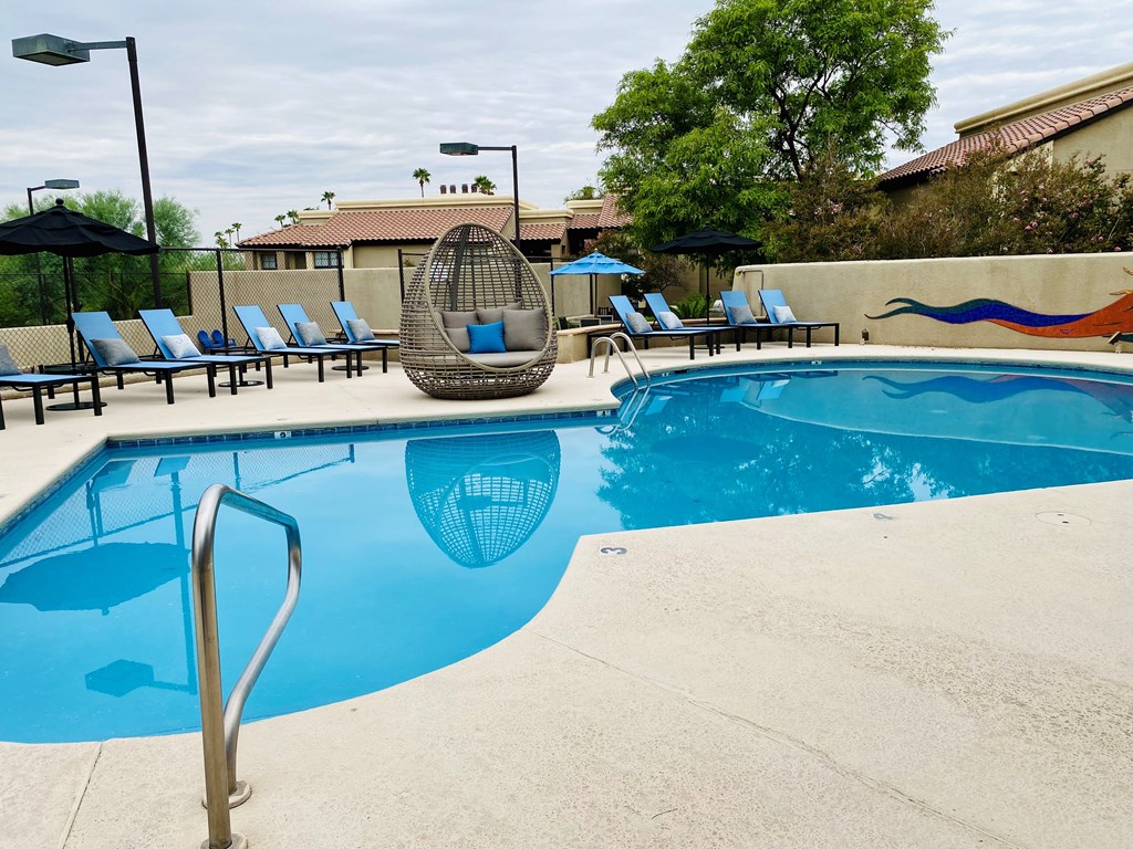 A pool with a blue water and a chair around it.