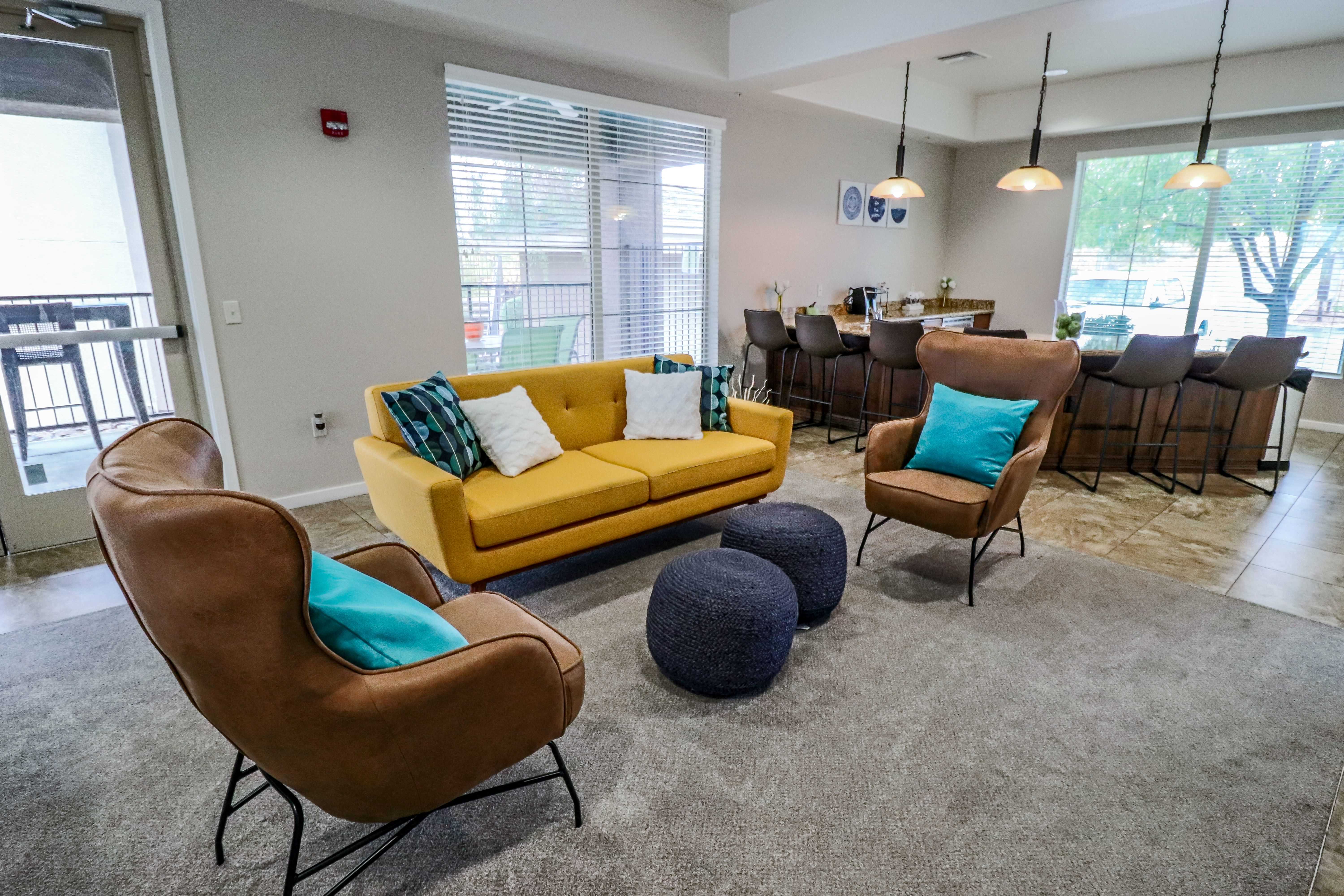A living room with a yellow couch and blue ottoman.