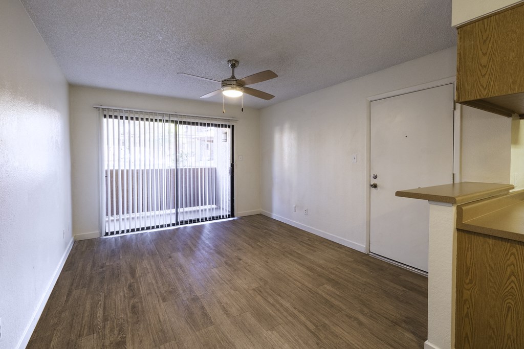 A room with a ceiling fan and sliding glass doors.
