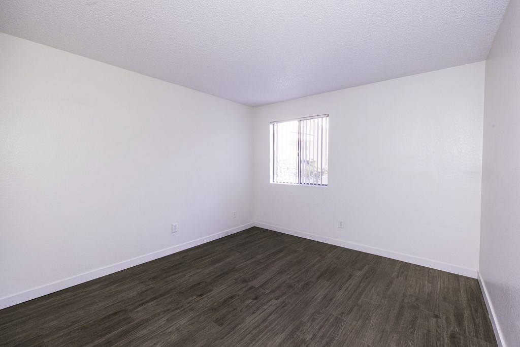 A room with wooden flooring and a window with blinds.