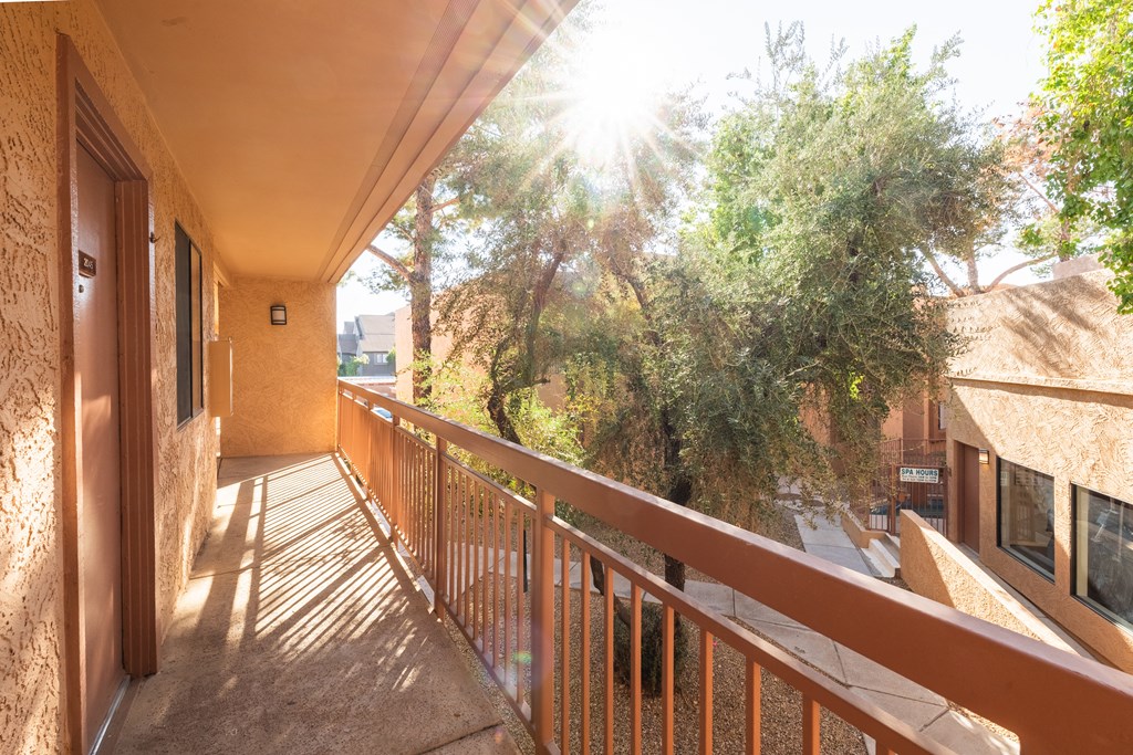 A balcony with a railing and a view of trees and buildings.