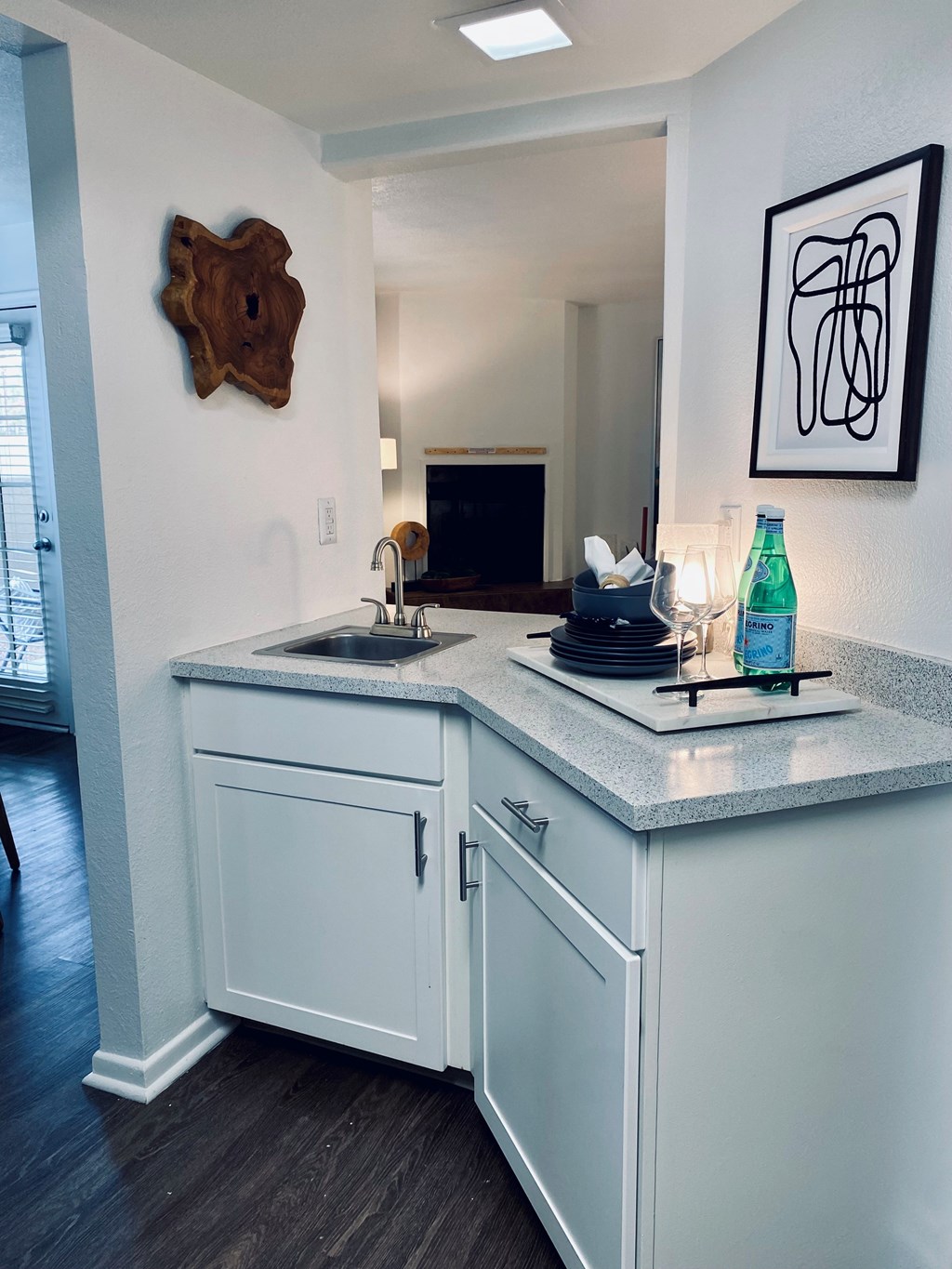 A kitchen with white cabinets and a wooden decoration on the wall.
