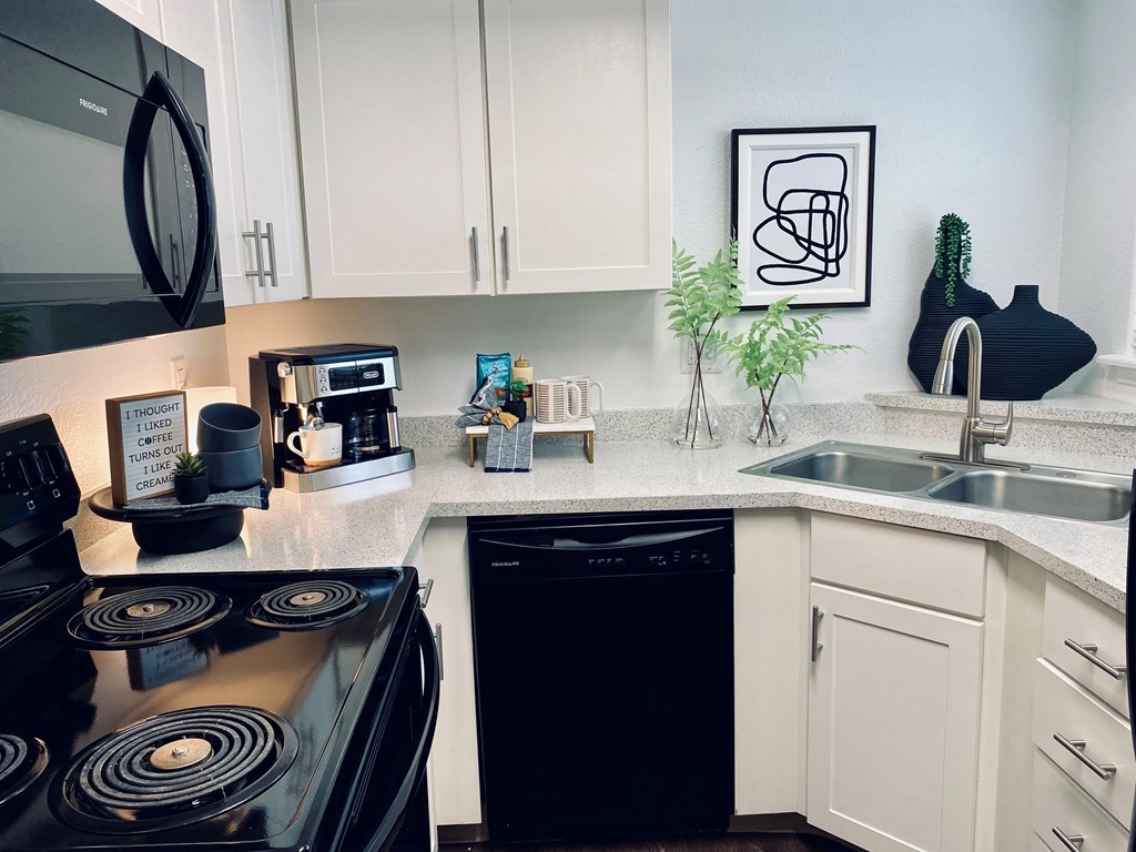 A black stove top oven sits in a kitchen with white cabinets.