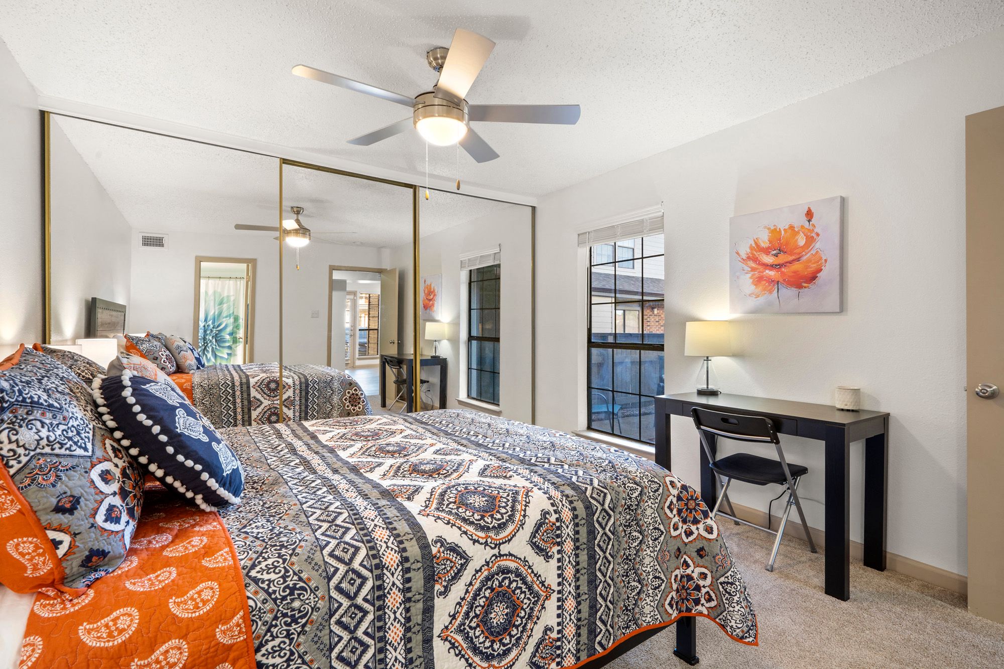 A bedroom with a large bed and a desk with a chair.