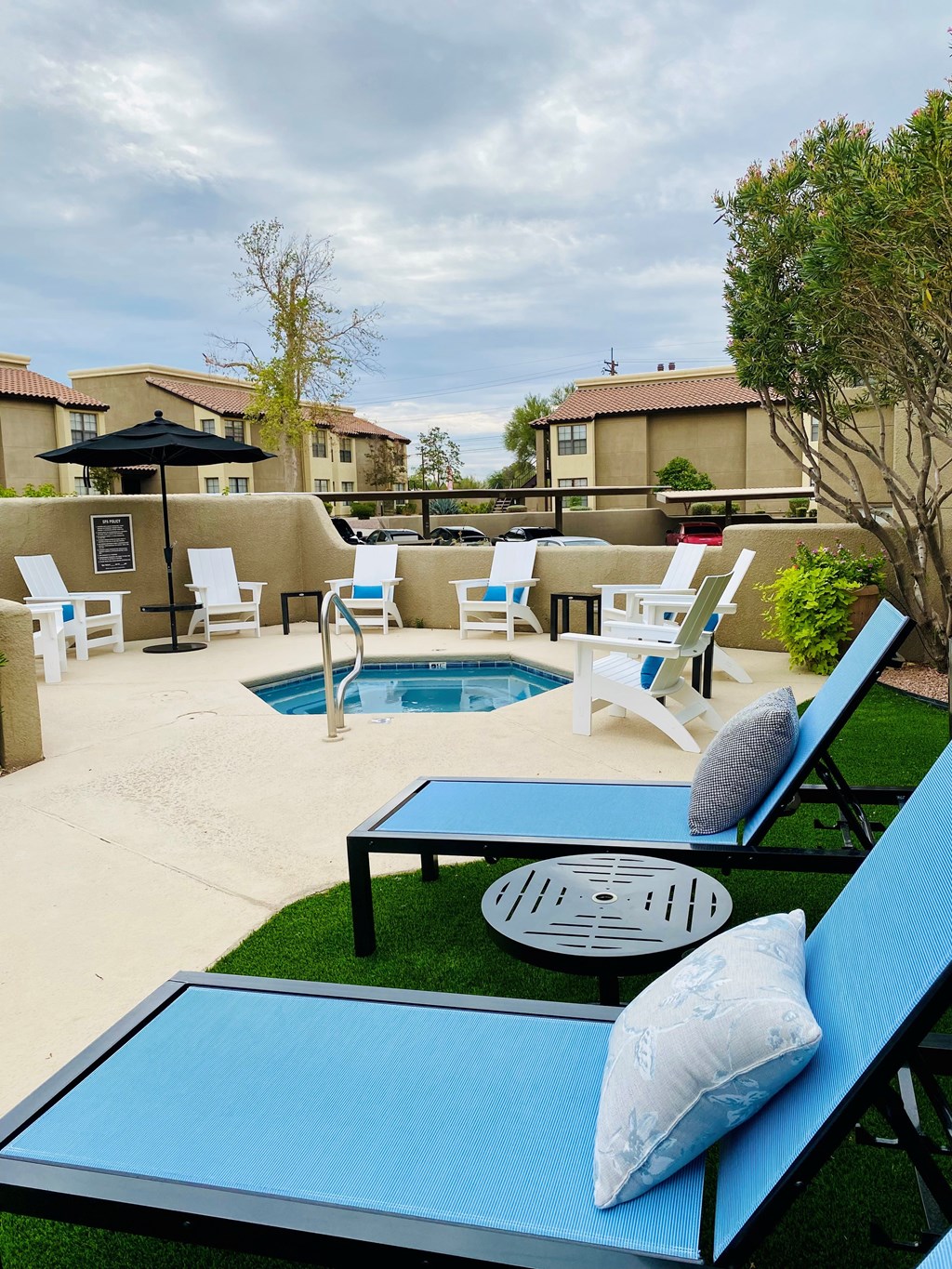 A poolside area with blue loungers and a black umbrella.