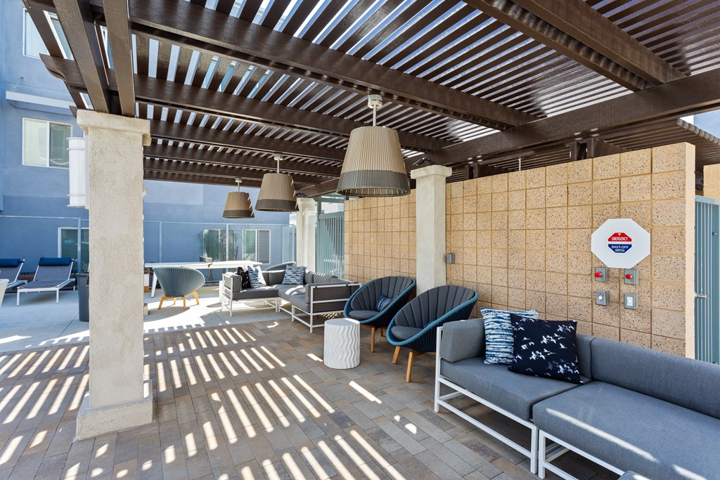 A patio with a couch, chairs, and a wall with a circular sign on it.