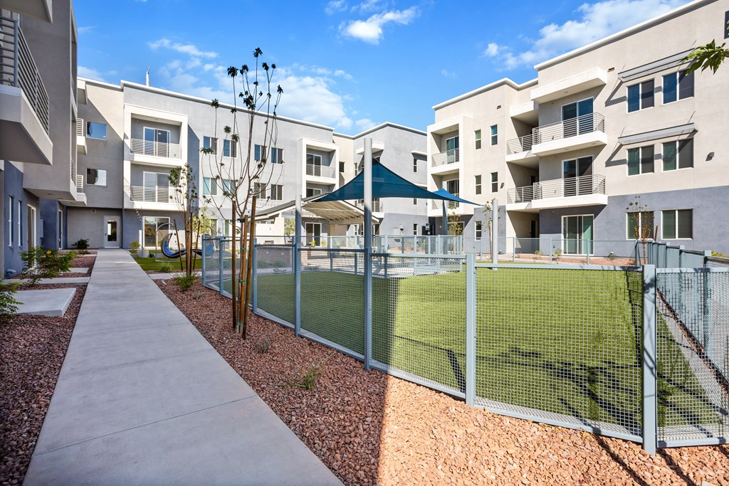A tennis court is enclosed by a fence in a residential area.