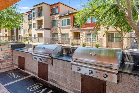 A row of outdoor BBQs are lined up on a brick wall.