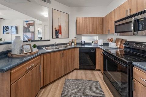 A modern kitchen with wooden cabinets and black appliances.