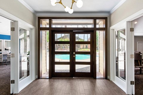 a view of a pool from a hallway with glass doors