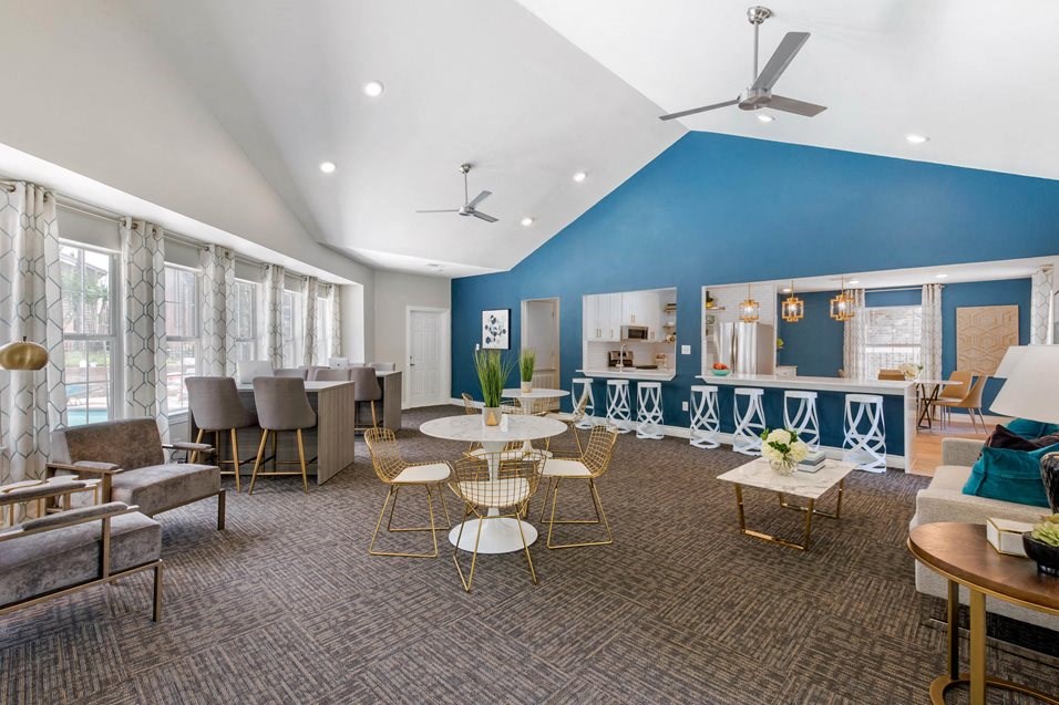 a lounge area with tables and chairs and a blue wall