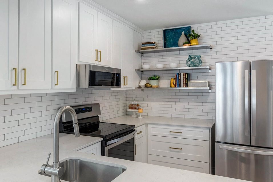 a white kitchen with stainless steel appliances and white cabinets
