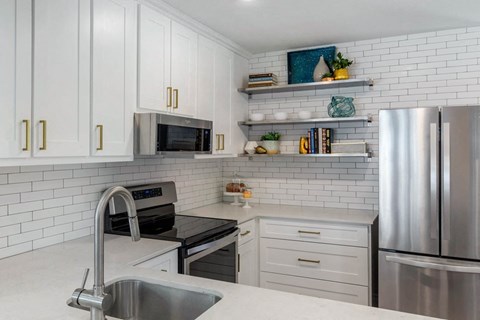 a white kitchen with stainless steel appliances and white cabinets