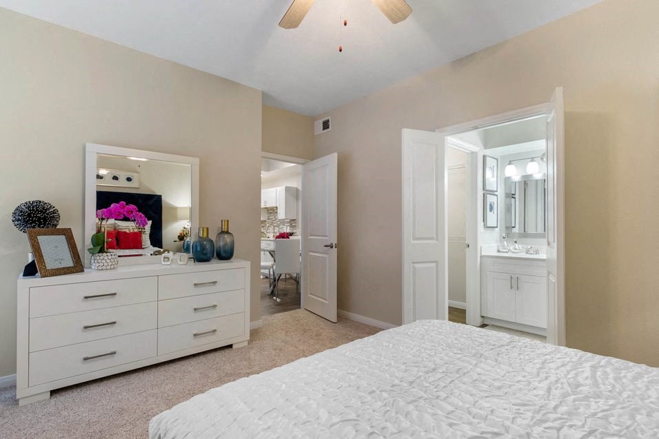 a white bedroom with a large bed and a mirror